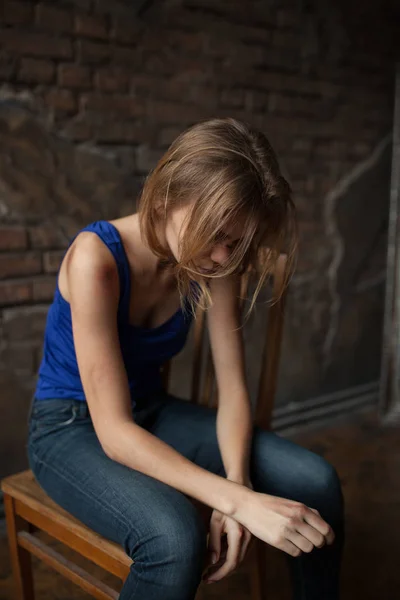 Smutná žena obětí domácího násilí a zneužívání sedí na židli s modřiny a rány na její tělo. — Stock fotografie