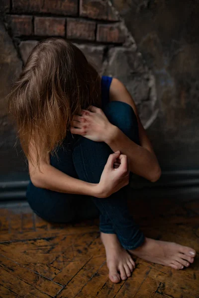 Sad woman victim of domestic violence and abuse sits on floor with bruises and wounds on her hands. — Stock Photo, Image