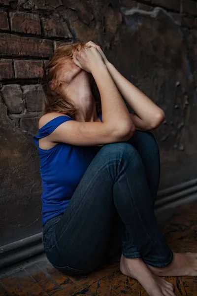 Crying woman victim of domestic violence and abuse sits on floor with bruises and wounds on her body. — Stock Photo, Image