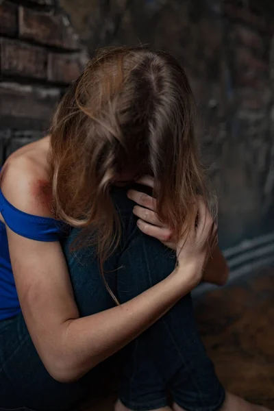 Femeia tristă victimă a violenței domestice și a abuzului stă pe podea cu vânătăi și răni pe corp. Closeup . — Fotografie, imagine de stoc