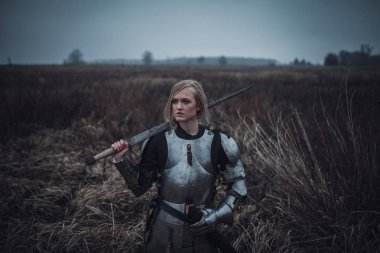 Kız Jeanne d'Arc zırh ve onun elinde kılıçla görüntü çayır üzerinde duruyor. Portre.