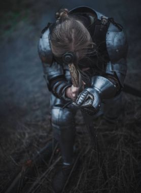 Kız Jeanne d'Arc zırh ve onun elinde kılıçla görüntü kuru ot arka planı diz çöker..