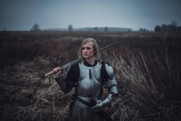 Chica en la imagen de Jeanne d 'Arc en armadura y con la espada en sus manos se encuentra en el prado. Primer plano. . —  Fotos de Stock