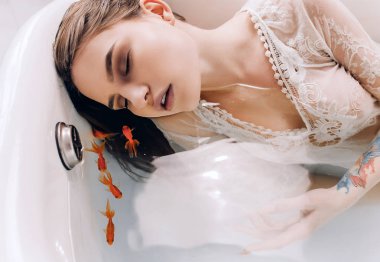 Genç kadın var içinde küvet su ve yüzme goldfishes ile rahatlayın. Portre.