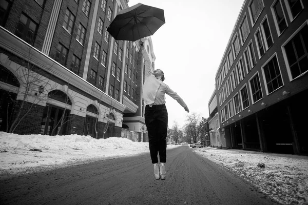 Balerin şemsiye attı ve şehir sokak atlama yüksektir. Siyah beyaz resim. — Stok fotoğraf