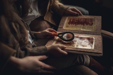 Kadınla yansımasındaki Sherlock Holmes kız çocuk oturur ve List büyüteç ile görünüyor.