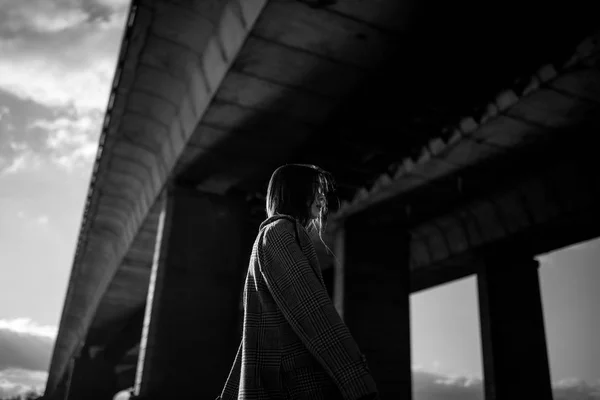 若い女性は、橋の下で歩きます。黒と白のイメージ. — ストック写真