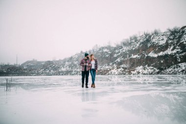 Kupa çay yürüyen donmuş gölün buz ile genç Çift.