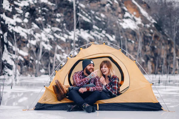 Jovem casal se senta e ri na tenda durante a caminhada de inverno . — Fotografia de Stock