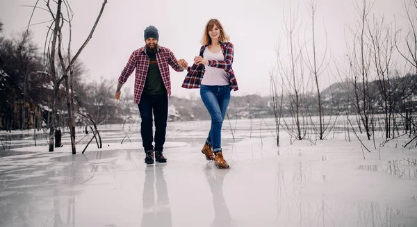 Jeune couple s'amuse pendant la promenade hivernale sur la glace du lac gelé . — Photo