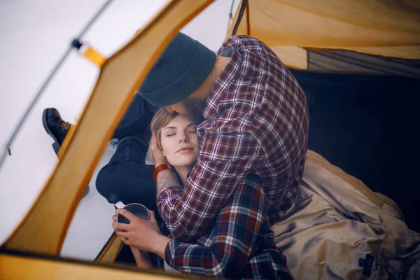 Jovens abraços de casal na tenda durante a caminhada de inverno. O tipo senta-se, rapariga mente — Fotografia de Stock