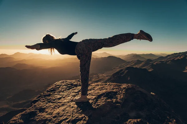妇女做瑜伽演习在西奈山上的悬崖上的背景日出. — 图库照片