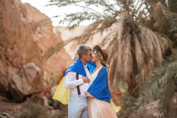 Pareja joven envuelta en la bandera de Ucrania se besan en el cañón. Primer plano. . — Foto de Stock