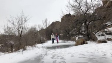 Genç çift eğlence parkı var ve erimiş su ile kaplı donmuş su birikintisi üzerinde sürmek. Sinek ayrı su sıçramalarına ve gençlik neşeyle gülüyor.