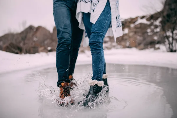 男性和女性腿在靴子站立在水坑与飞行分开水飞溅. — 图库照片
