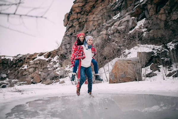 Genç adam kız arkadaşı erimiş su birikintisi sırtında taşır. Çift gülüyor.