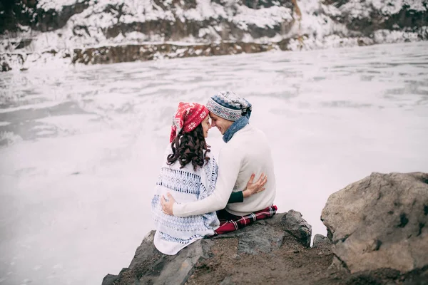 Couple is hugging and smiling against background of snow-covered hills and frozen lake. — Stock Photo, Image