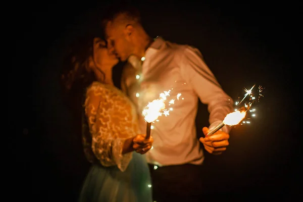 Braut und Bräutigam küssen und verbrennen nachts Bengalische Lichter. Nahaufnahme. — Stockfoto