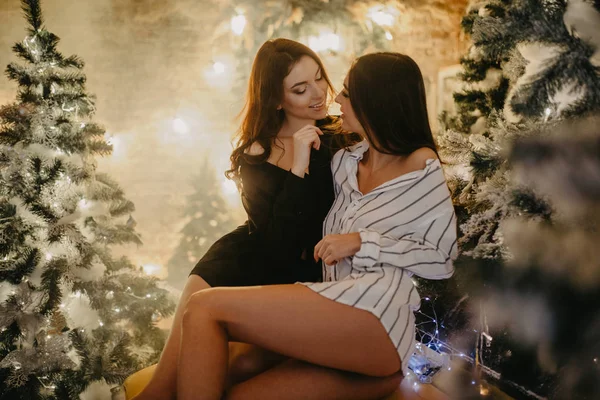 Lezbiyen çift Noel süslemelerinin arka planında oturuyor — Stok fotoğraf