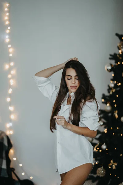 Mujer joven se levanta contra el fondo del árbol de Navidad — Foto de Stock