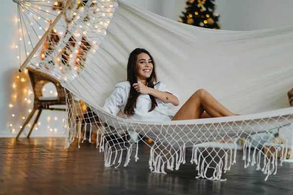 Jovem mulher encontra-se em rede e sorri contra o fundo da árvore de Natal — Fotografia de Stock