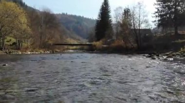 İnsansız hava aracı, bir dağ nehrinin akan sularından Karpatlar 'daki küçük köprüye doğru ateş ediyor. Yakın çekim..