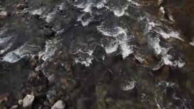 Taşların üzerinden akan bir dağ nehrinin üzerinde yakın çekim..