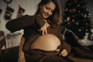 Hamile kadın eğleniyor ve karnıyla oynuyor. 