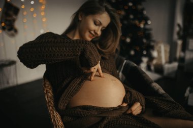 Hamile kadın eğleniyor ve karnıyla oynuyor. 