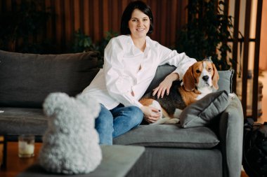 Kanepede oturan bir kadın av köpeğinin yanında..