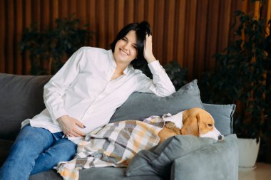 Bir kadın ekose bir köpeğin yanına oturur..