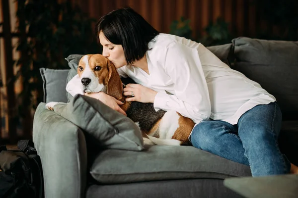 Una mujer yace junto a un perro, lo abraza y lo besa . — Foto de Stock