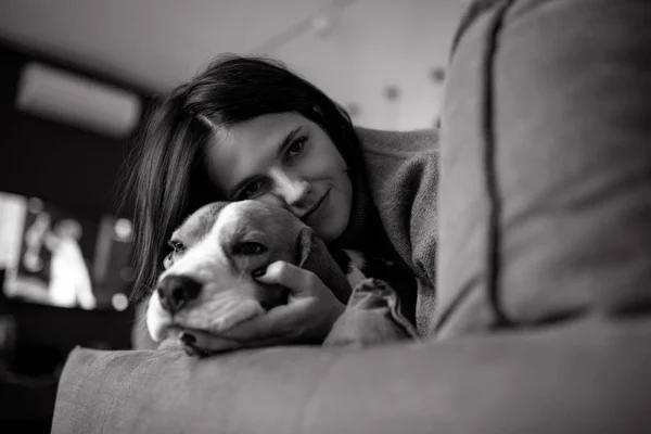 Una mujer yace junto a un perro y lo abraza . — Foto de Stock