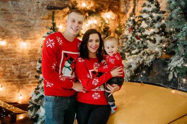 Gezin met kleine zoon staat tegen de achtergrond van een kerstboom — Stockfoto