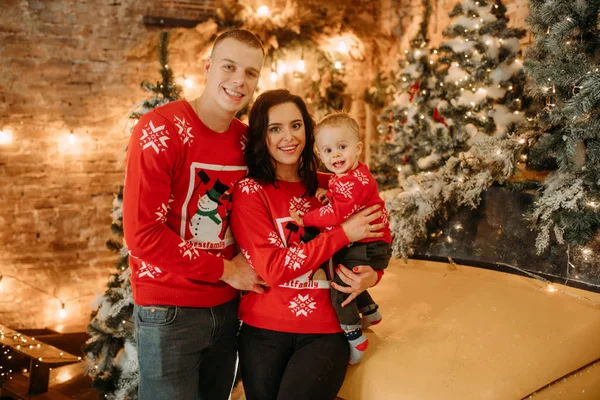 Família com filho pequeno está contra o fundo de uma árvore de Natal — Fotografia de Stock