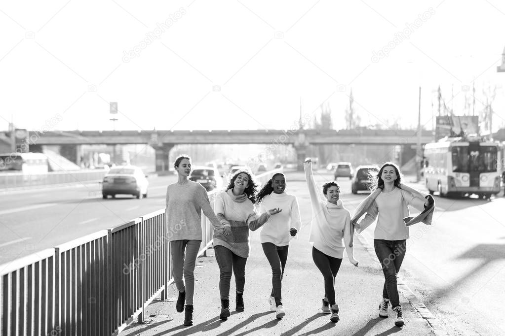 Multiracial group of friends walks and has a fun on city street.