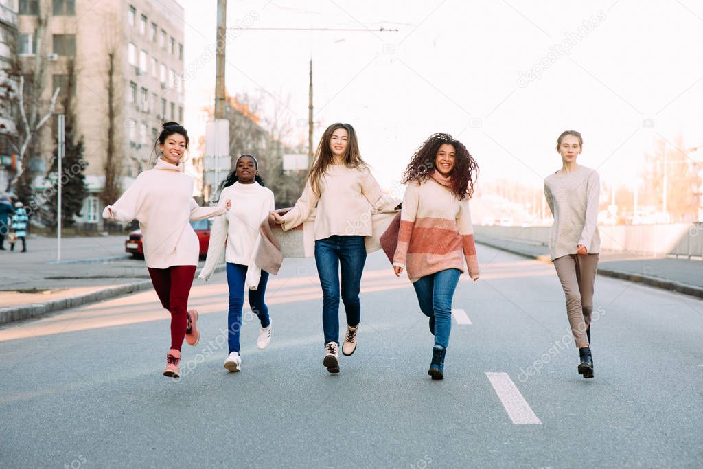 Multiracial group of friends runs and has a fun on city street.