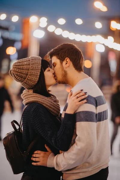Jovem casal fica e beijos no fundo da cidade luzes . — Fotografia de Stock