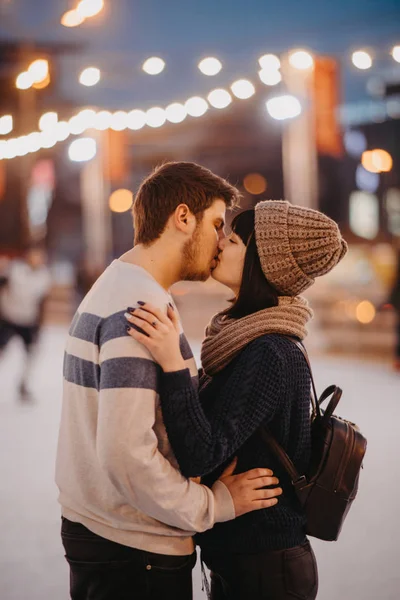 Jovem casal fica e beijos no fundo da cidade luzes . — Fotografia de Stock