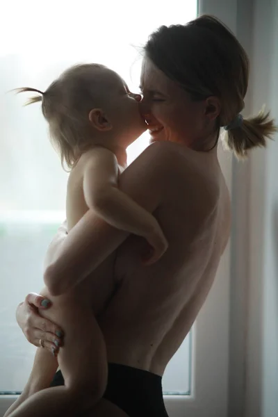 Мама с ребенком стоит у окна . — стоковое фото