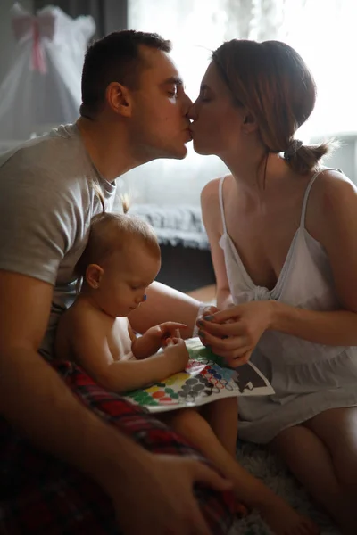 Bebé juega al lado de besar padres . — Foto de Stock