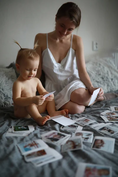 Мама сидит со своей маленькой дочерью и смотрит фотографии . — стоковое фото