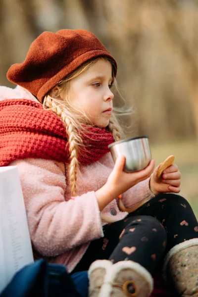 Chica bebe té caliente y come galletas en el bosque . —  Fotos de Stock