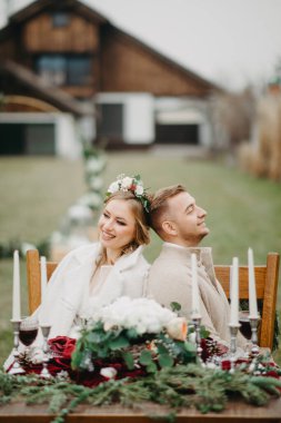 Mutlu yeni evliler ziyafet masasının yanına oturur ve gülümser..