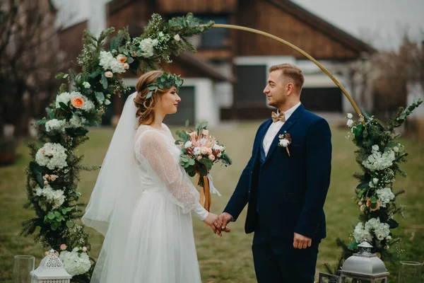 Nygifta Står Bakgrunden Bröllopsbågen Och Håller Varandras Händer — Stockfoto