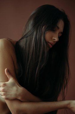 Stüdyoda poz veren genç üstsüz kadın..