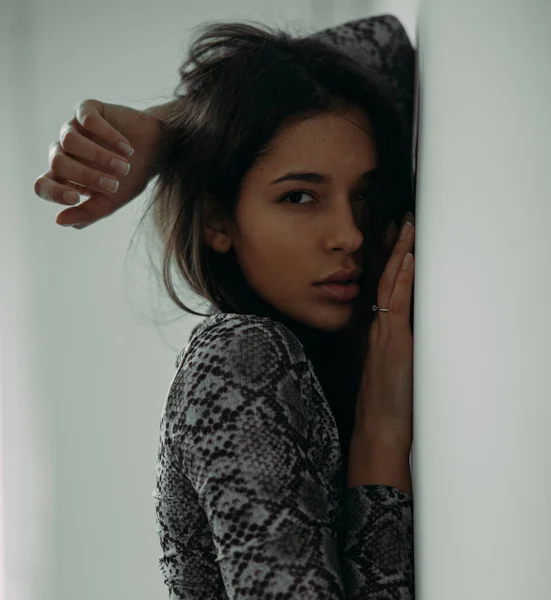 Young woman in a blouse posing in the studio on a gray background.