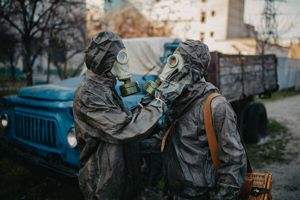 Couple in love hugs in NBC protective suits and gas masks. Concept of a preventive measures and protection for coronavirus COVID 19 pandemic and other global dangers.