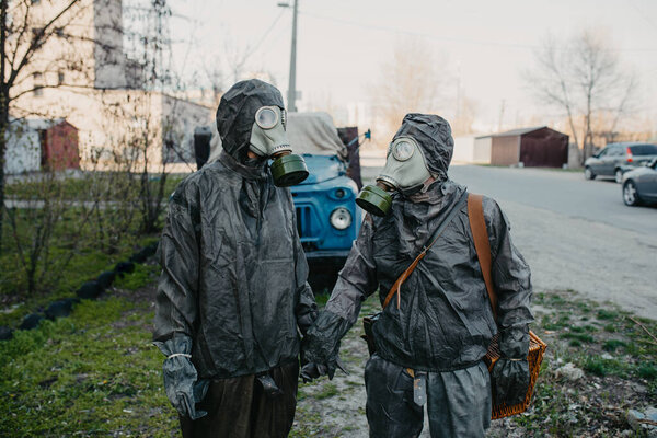 Couple in love holds hands in NBC protective suits and gas masks. Concept of a preventive measures and protection for coronavirus COVID 19 pandemic and other global dangers.