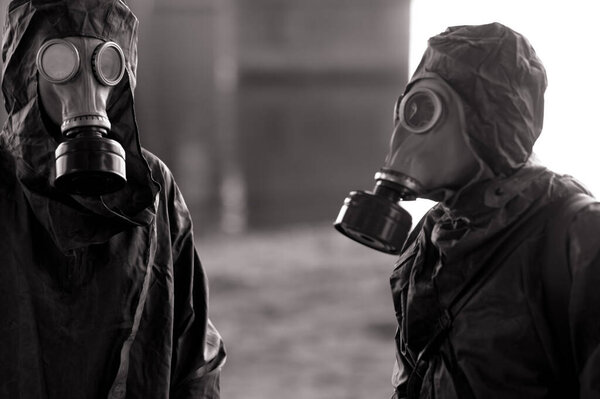 Two persons in NBC protective suits and gas masks. Concept of a preventive measures and protection for coronavirus COVID 19 pandemic and other global dangers.